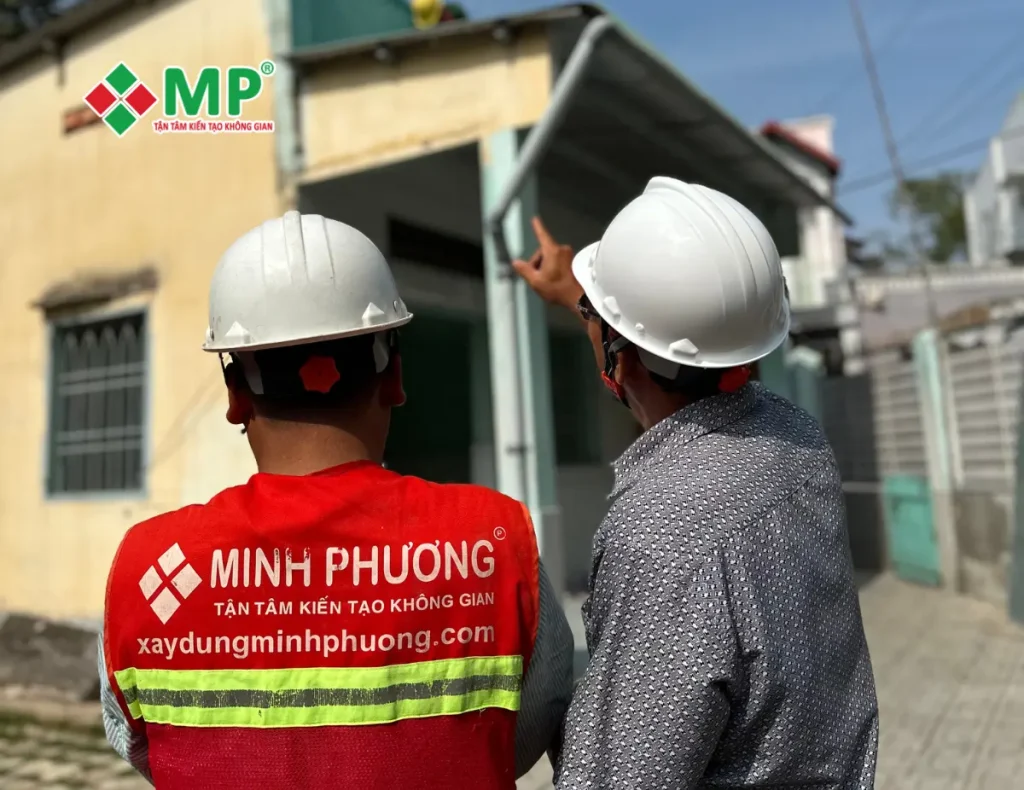 đội ngũ kỹ sư/kiến trúc sư của Minh Phương đang sử dụng dụng cụ chuyên nghiệp (thước laser, sổ tay, máy ảnh, đèn pin kiểm tra góc khuất) để đo đạc, kiểm tra một bức tường, kiểm tra hệ thống kỹ thuật hoặc trao đổi chuyên môn với khách hàng ngay tại công trình. Thể hiện sự tỉ mỉ, chuyên nghiệp và tương tác với khách hàng.
